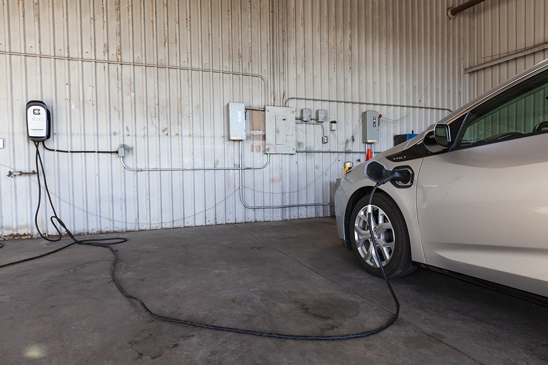 grey car using ev charger in orange county in a garage